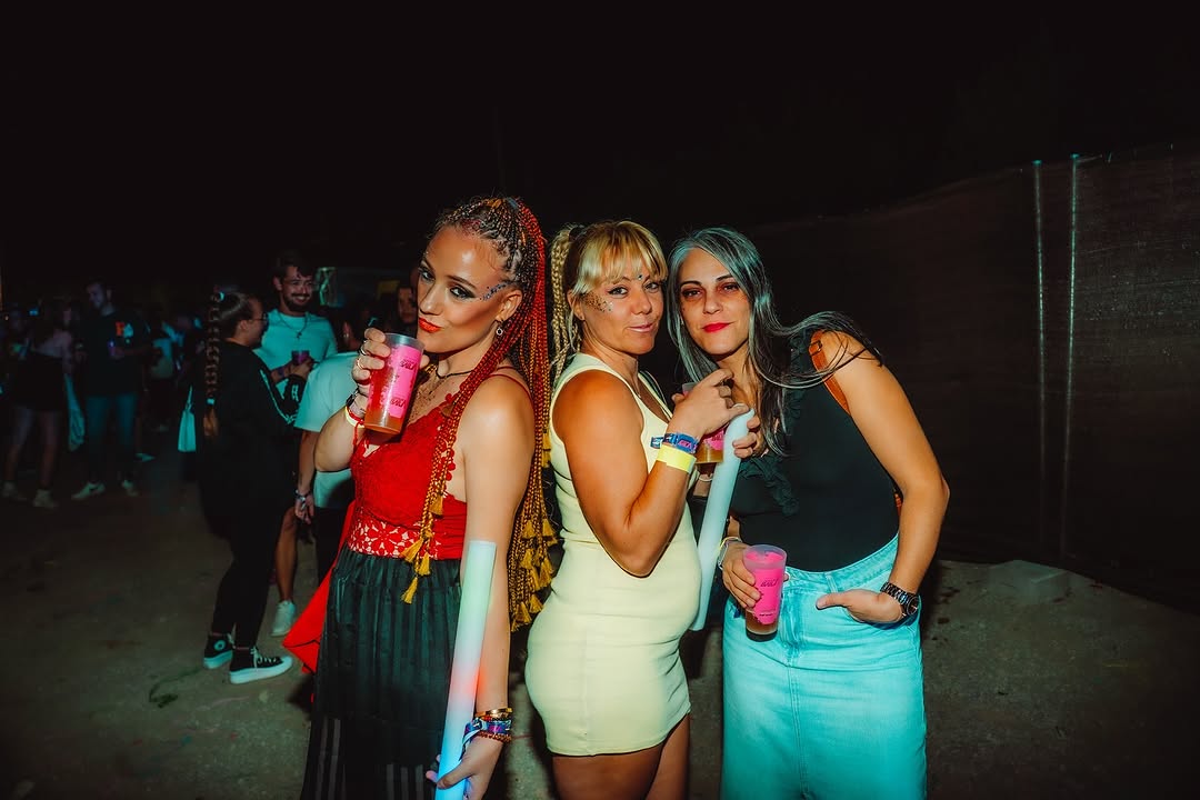 Tres asistentes posando de noche con barras de luz